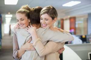 Happy businesswomen hugging in office