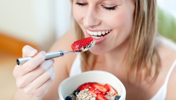 Charming woman eating muesli with fruits