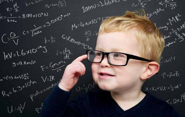 Smart young boy stood infront of a blackboard