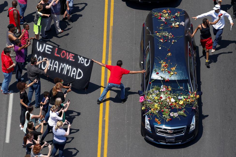 Well wishers holding a banner touch the hearse carrying the body of Muhammad Ali in Louisville Kentucky