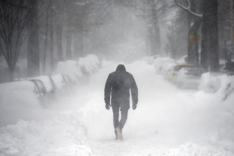 A man walks along a street covered by snow during a winter storm in Washington