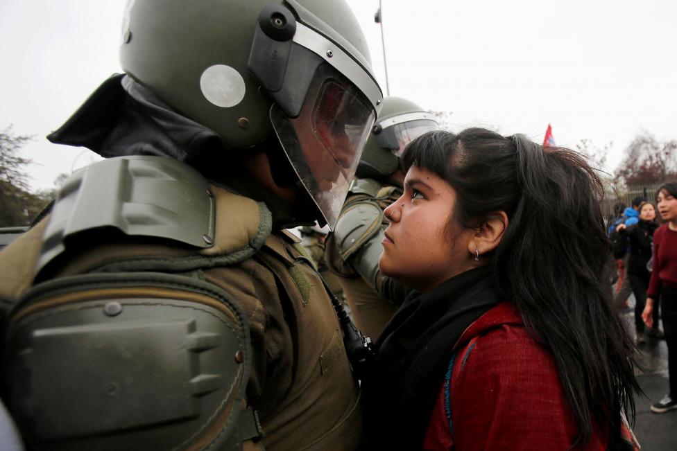 A demonstrator looks at a riot policeman during a protest marking the country's 1973 military coup in Santiago, Chile