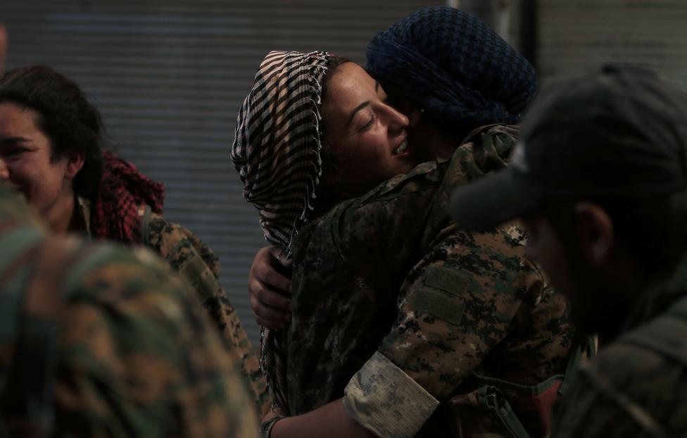 Syria Democratic Forces (SDF) female fighters embrace each other in the city of Manbij, in Aleppo Governorate