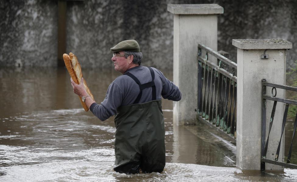 A resident brings French baguettes to his mother's flooded house after heavy rain falls in Chalette-sur-Loing Montargis