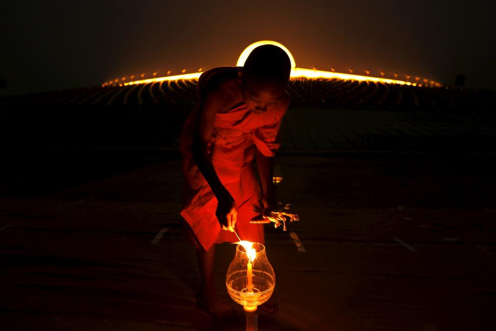 A Buddhist monk lights a candle at Wat Phra Dhammakaya during a ceremony on Makha Bucha Day in Pathum Thani province, north of Bangkok