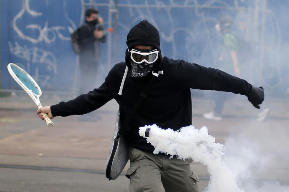 A protestor uses a tennis racket to return a tear gas canister during a demonstration to protest the government's proposed labour law reforms in Nantes