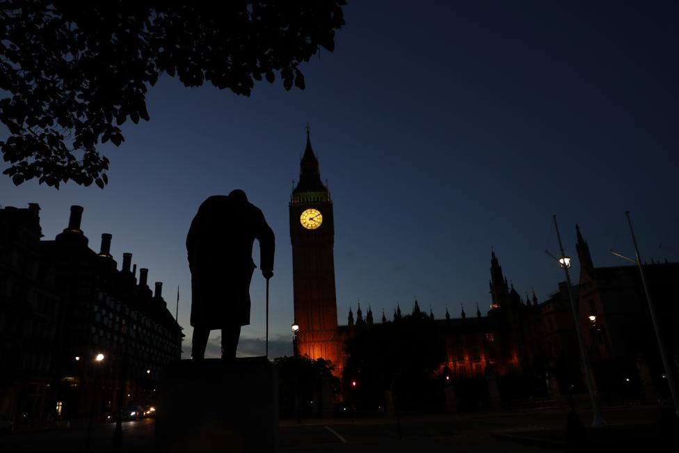 Dawn breaks behind the Houses of Parliament and the statue of Winston Churchill in Westminster, London, Britain