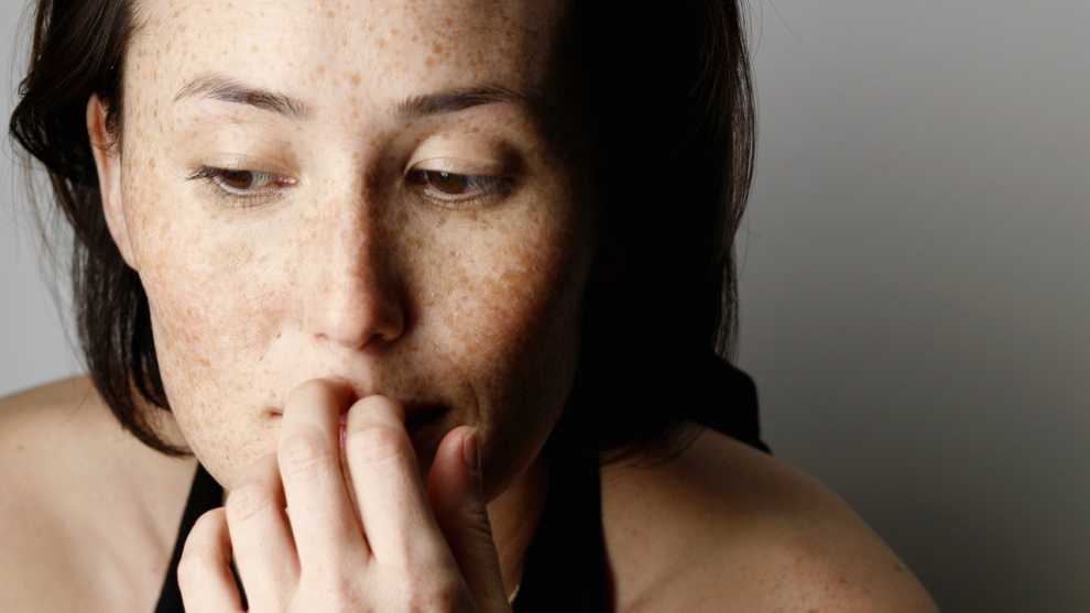 Young woman with pensive expression, hand on mouth