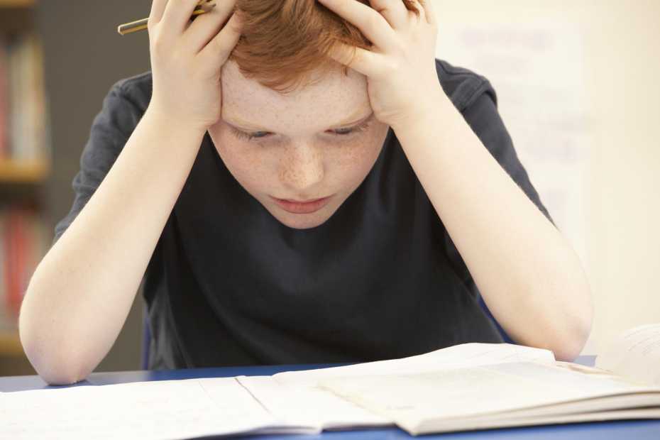 Stressed Schoolboy Studying In Classroom