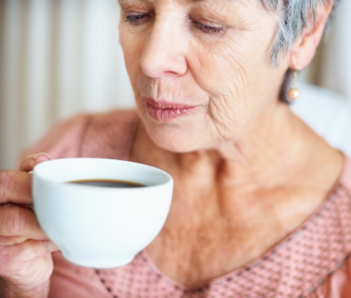 Senior lady blowing her hot coffee