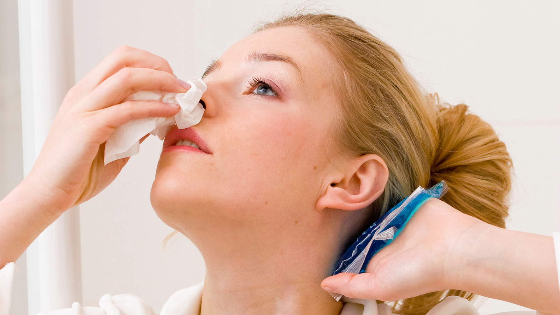 Woman treating a nosebleed