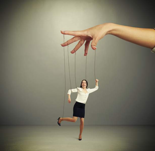 womans hand manipulating puppet over dark background