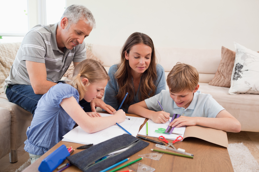 Parents helping their children to do their homework in their living room