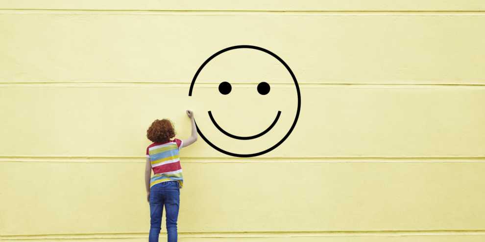 Girl drawing smiley face on to a wall