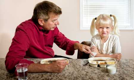 A little girl refuses to eat what Dad has cooked for dinner.
