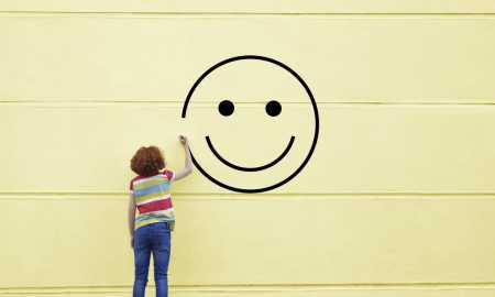 Girl drawing smiley face on to a wall