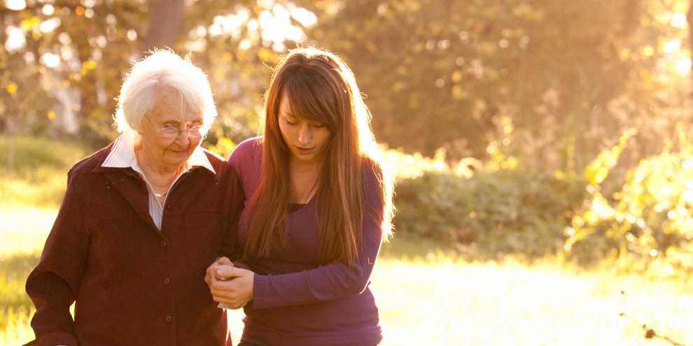 Young Woman helping Older Women walk in woods