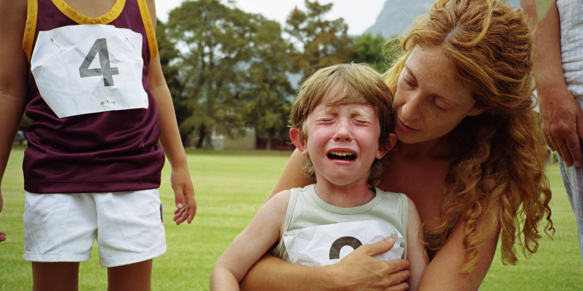 Boy (4-6) crying while being comforted by mother at school sports day