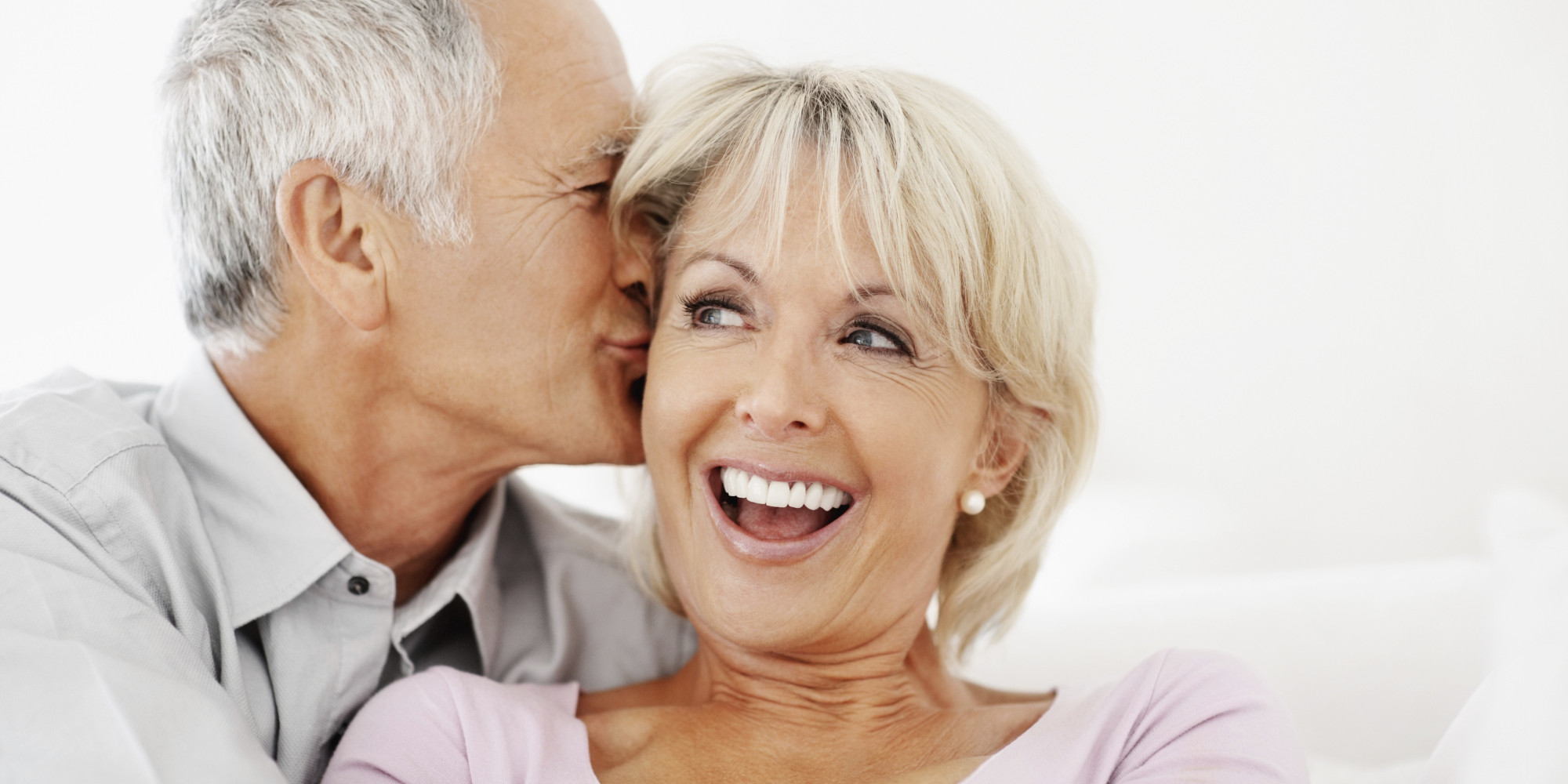 Romantic senior man kissing a cheerful woman on cheek