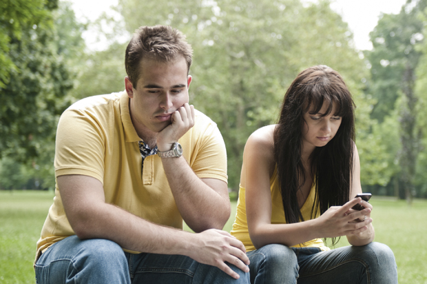 Young couple sitting outdoors on bench having relationship problems