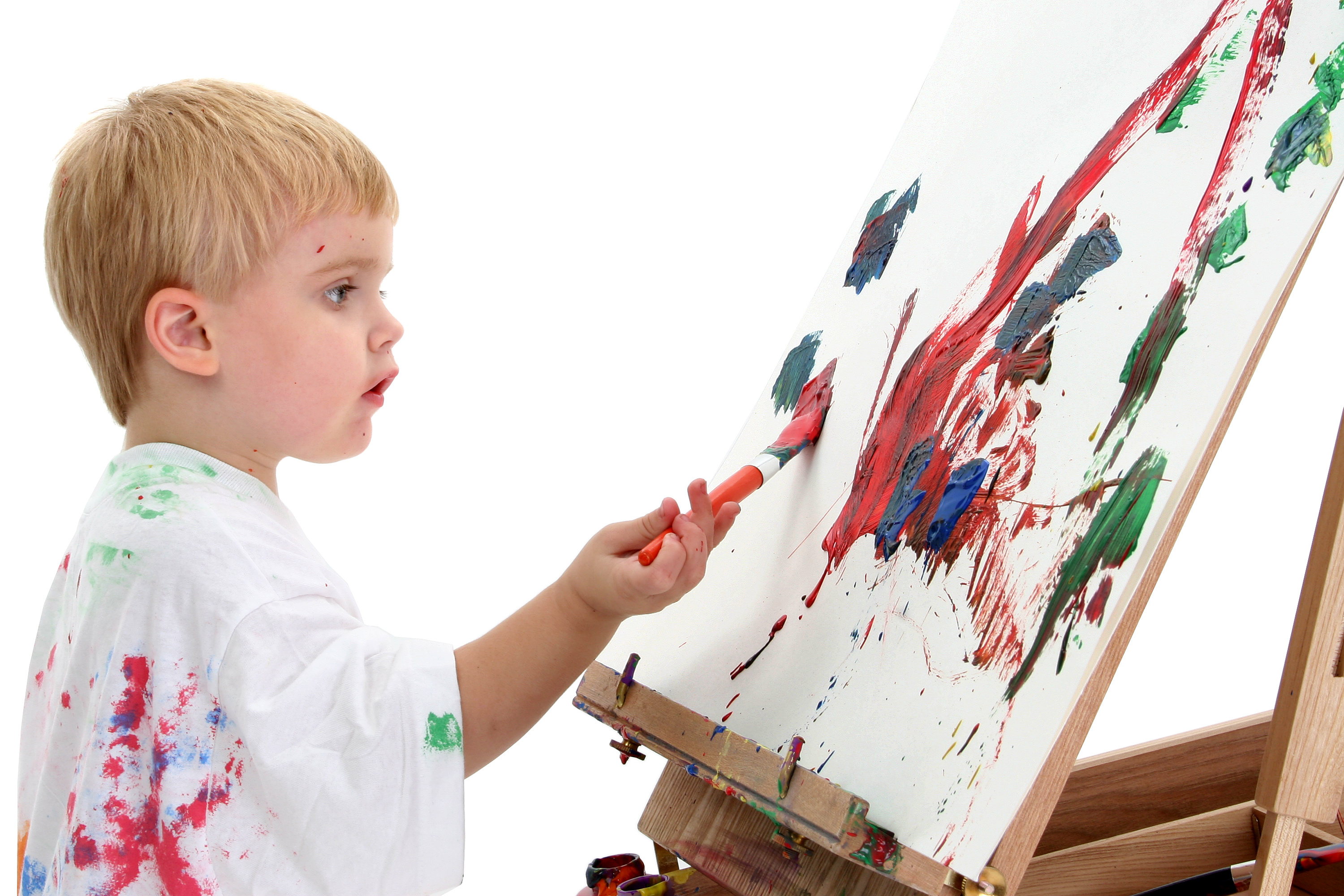 Toddler boy in big white shirt covered in paint at easel. American blonde caucasian boy. Shot over white background.