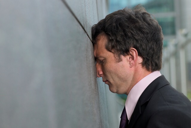 Businessman with face pressed against wall, profile, close-up