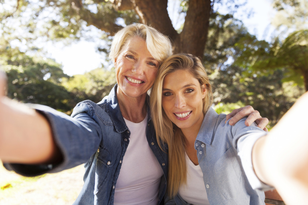 happy senior woman and daughter taking selfie together