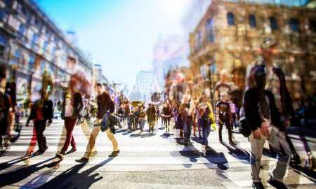 Crowd of anonymous people walking on busy city street