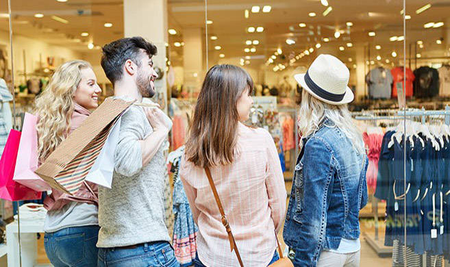 Junge Leute beim Shopping im Einkaufszentrum vor einem Modeladen