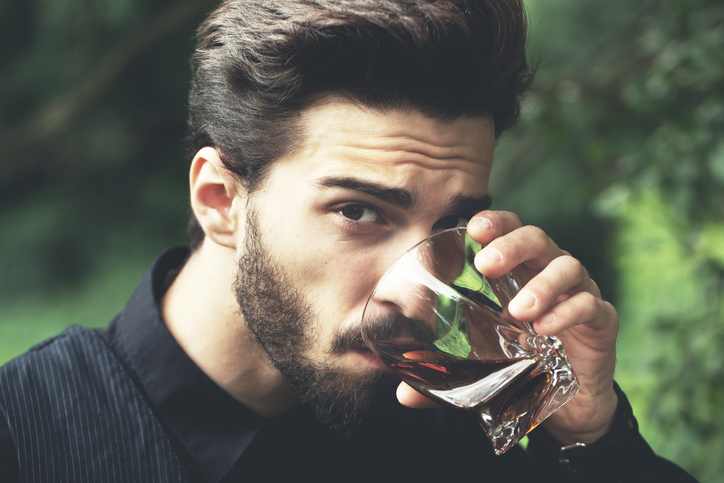 Bearded man posing outdoors with alcohol. Special toned image colors.