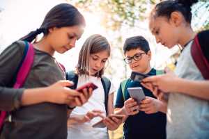 Group of kids playing video games on smart phone after school